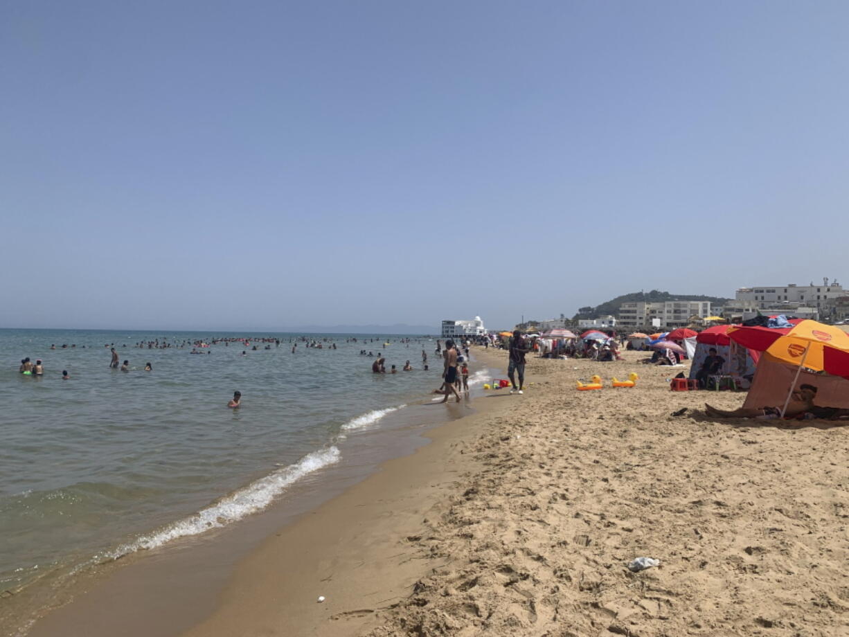 Tunisians relax on La Marsa beach outside Tunis, Sunday, Aug. 1, 2021, as the country remained in limbo more than a week after President Kais Saied fired the prime minister, froze the parliament and took on executive powers.