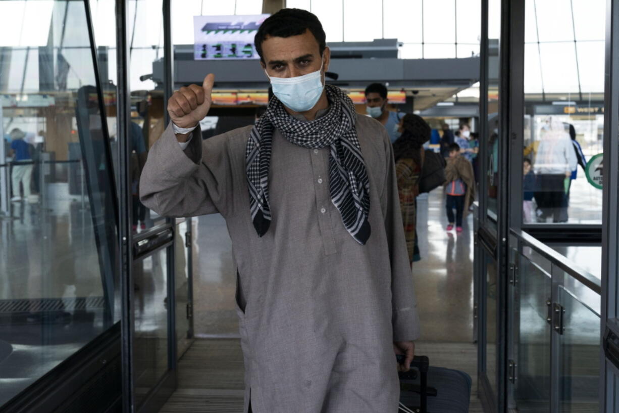 Families evacuated from Kabul, Afghanistan, walk through the terminal before boarding a bus after they arrived at Washington Dulles International Airport, in Chantilly, Va., on Friday, Aug. 27, 2021.