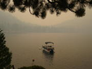 Smoke from the Caldor Fire, shrouds Fallen Leaf Lake near South Lake Tahoe, Calif., Tuesday, Aug. 24, 2021. The massive wildfire, that is over a week old, has scorched more than 190 square miles, (492 square kilometers) and destroyed hundreds of homes since Aug. 14. It is now less than 20 miles from Lake Tahoe.