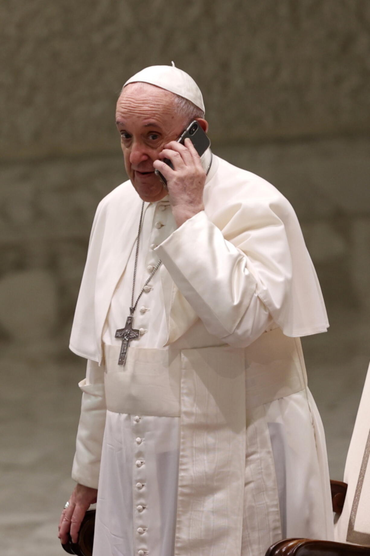 Pope Francis speaks on a cellphone given to him by his aide Piergiorgio Zanetti, at the end of his weekly general audience Wednesday in the Paul VI hall at the Vatican.