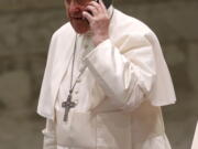 Pope Francis speaks on a cellphone given to him by his aide Piergiorgio Zanetti, at the end of his weekly general audience Wednesday in the Paul VI hall at the Vatican.