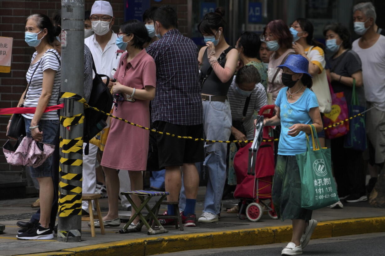 People wearing face masks to help curb the spread of the coronavirus line up outside a bakery shop to buy cookies in Shanghai, China, Friday, Aug. 27, 2021.