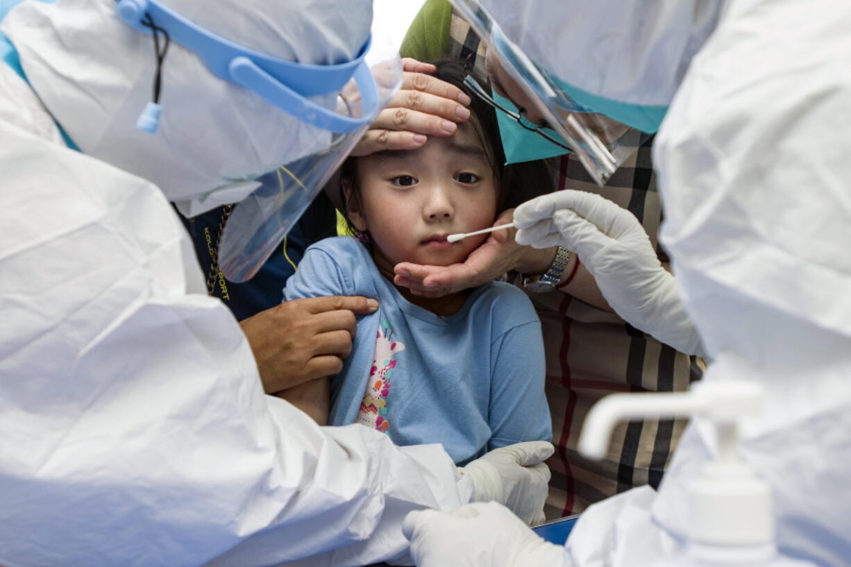 A child reacts to a throat swab during mass testing for COVID-19 in Wuhan in central China's Hubei province Tuesday, Aug. 3, 2021. The coronavirus's delta variant is challenging China's costly strategy of isolating cities, prompting warnings that Chinese leaders who were confident they could keep the virus out of the country need a less disruptive approach.