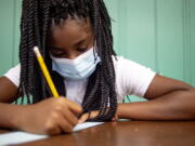 Sixth-grader Adriana Campbell, 11, jots down her name as she starts to work on her first assignment during the first day of school on Wednesday, Aug. 4, 2021 at Freeman Elementary School in Flint, Mich. " Schools have begun reopening in the U.S. with most states leaving it up to local schools to decide whether to require masks.