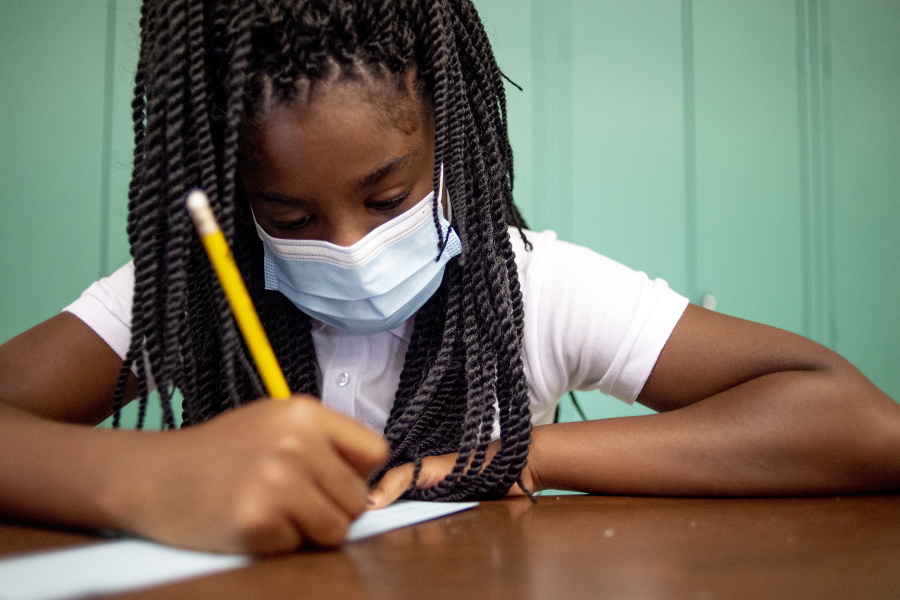 Sixth-grader Adriana Campbell, 11, jots down her name as she starts to work on her first assignment during the first day of school on Wednesday, Aug. 4, 2021 at Freeman Elementary School in Flint, Mich. " Schools have begun reopening in the U.S. with most states leaving it up to local schools to decide whether to require masks.