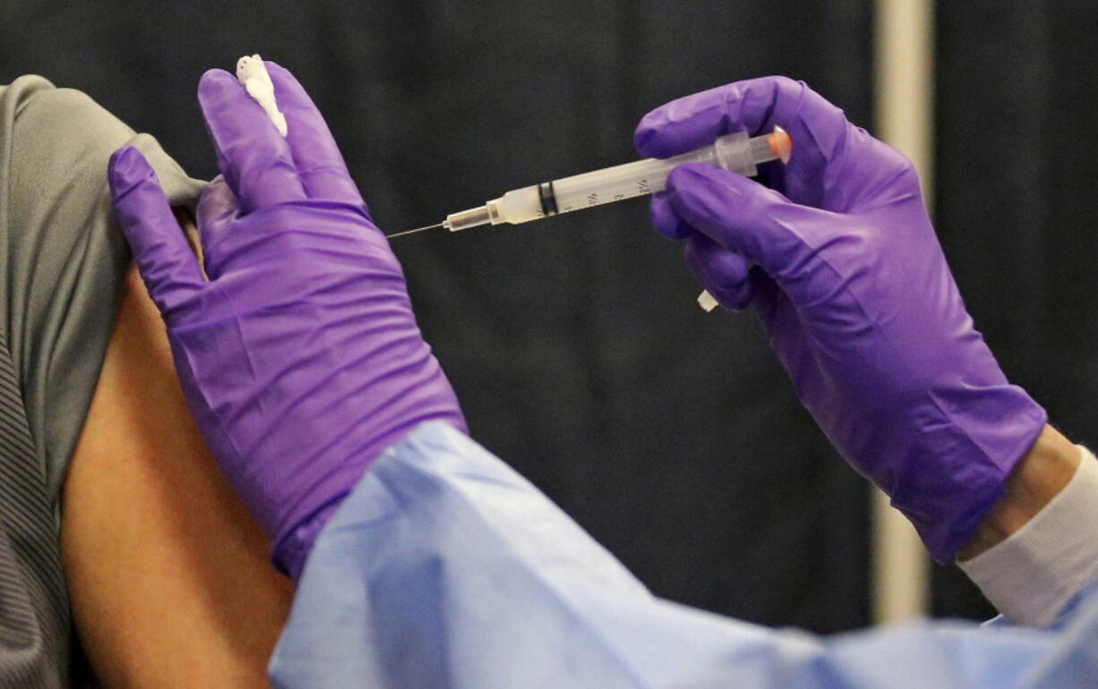 FILE - A man gets a COVID-19 vaccine at a mass vaccination site at the Natick Mall on Wednesday, Feb. 24, 2021, in Natick, Mass.  U.S. experts are expected to recommend COVID-19 vaccine boosters for all Americans, regardless of age, eight months after they received their second dose of the shot, to ensure lasting protection against the coronavirus as the delta variant spreads across the country. An announcement was expected as soon as this week, with doses beginning to be administered widely once the Food and Drug Administration formally approves the vaccines.