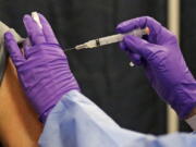 FILE - A man gets a COVID-19 vaccine at a mass vaccination site at the Natick Mall on Wednesday, Feb. 24, 2021, in Natick, Mass.  U.S. experts are expected to recommend COVID-19 vaccine boosters for all Americans, regardless of age, eight months after they received their second dose of the shot, to ensure lasting protection against the coronavirus as the delta variant spreads across the country. An announcement was expected as soon as this week, with doses beginning to be administered widely once the Food and Drug Administration formally approves the vaccines.