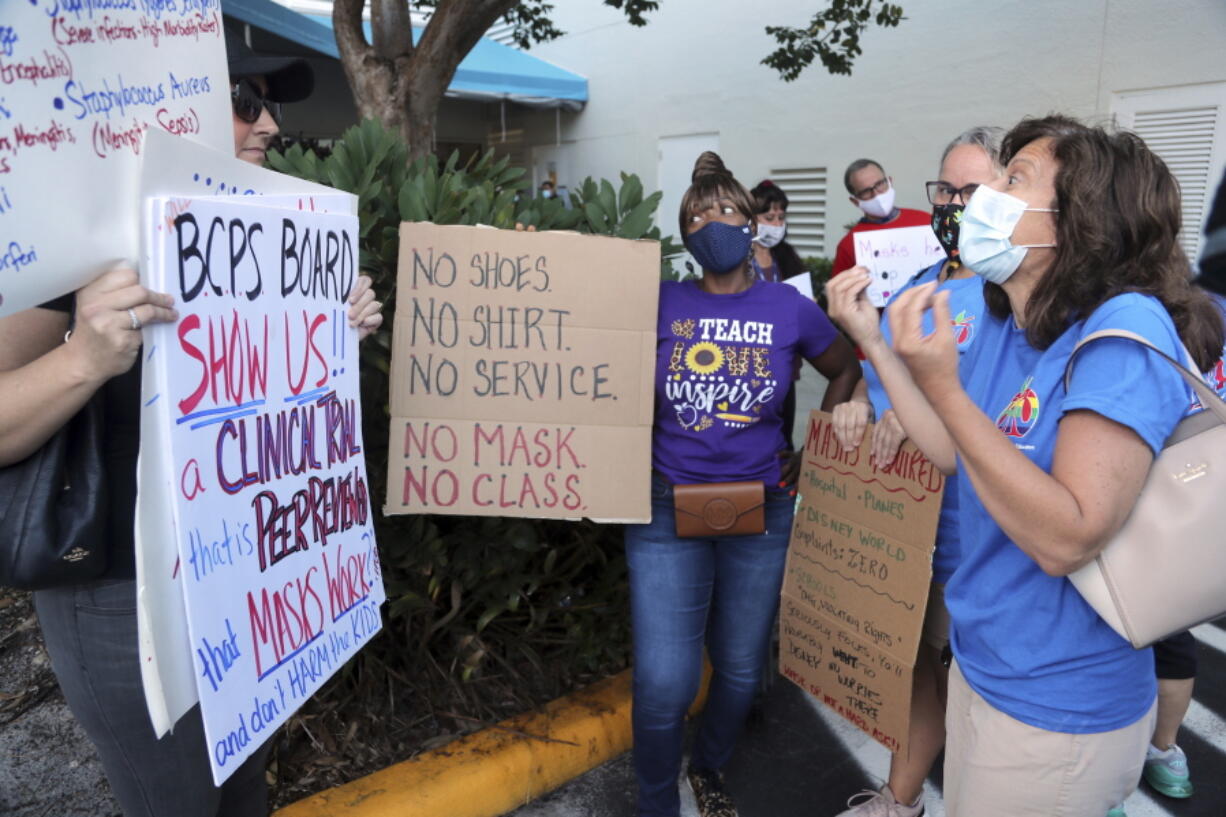 Yvonne Moniz, right, a special needs teacher at Challenger Elementary, along with Oakland Park Elementary third grade teacher Donna Sacco, second from right, and Oriole Elementary fourth grade teacher Yolanda Smith, center, tries to persuade anti-mask protester Heather Tanner that all students need to wear masks to protect the most vulnerable. during a protest outside of a Broward County School Board meeting, Tuesday, Aug. 10, 2021, in in Fort Lauderdale, Fla., to discuss a possible mask mandate when school starts next week.