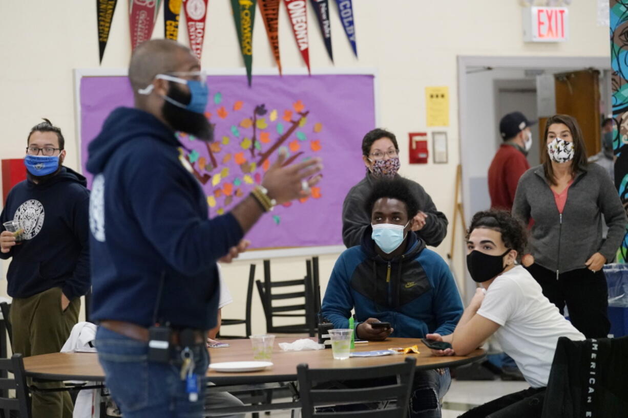 FILE- In this Oct. 29, 2020, file photo, students, teachers, administrators and counselors listen as principal Malik Lewis, second from left, teaches them a history lesson at West Brooklyn Community High School in New York. All New York City public school teachers and other staffers will have to get vaccinated against the coronavirus, officials said Monday, Aug. 23, 2021, as the nation's largest school system prepares for classes to start next month.