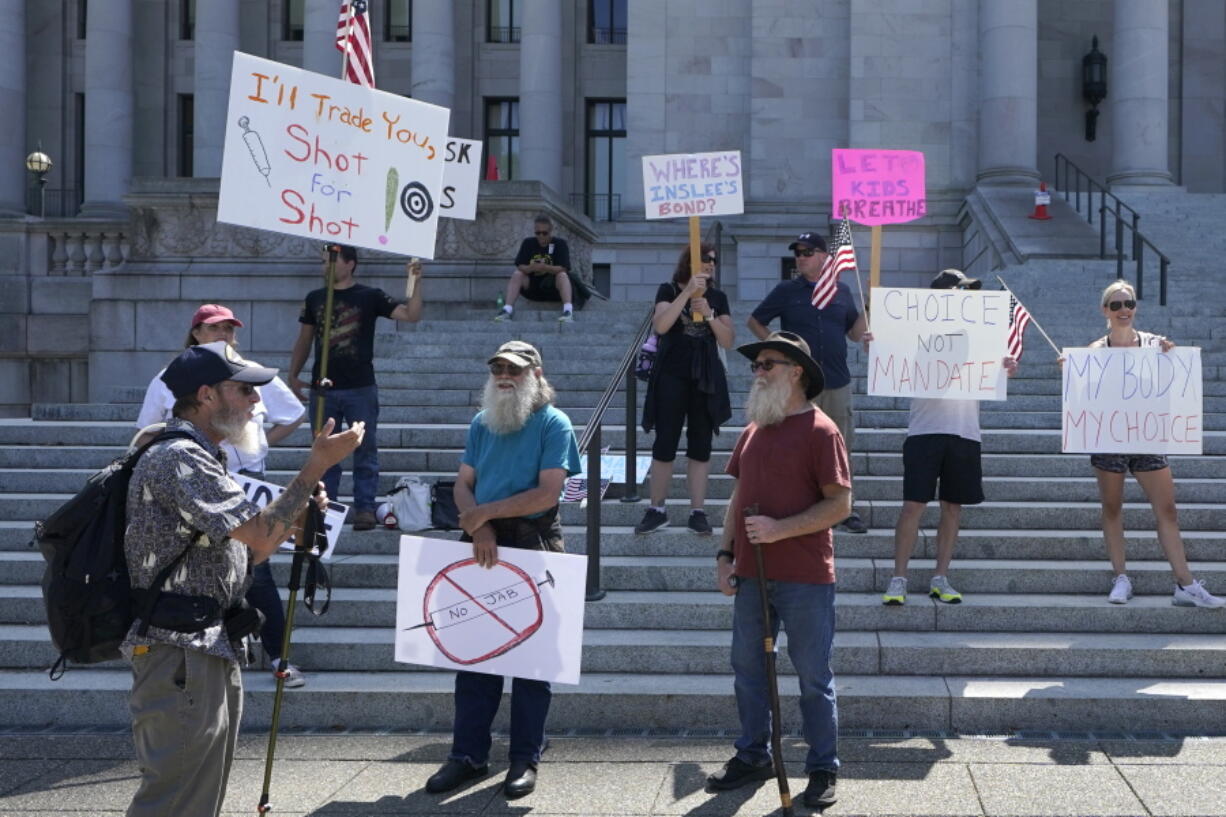 FILE - Protesters who oppose mask and COVID-19 vaccine mandates gather outside the Legislative Building, Wednesday, Aug. 18, 2021, at the Capitol in Olympia, Wash. A growing number of communities are moving to require teachers to get vaccinated against COVID-19 as part of aggressive campaigns to ward off the delta variant, which has infected hundreds of thousands of children in the United States. While some school districts are allowing teachers to opt out of vaccine requirements with weekly testing, New York City, Philadelphia, Chicago and St. Louis have taken tougher stances by limiting exemptions to bona fide medical and religious reasons. (AP Photo/Ted S.