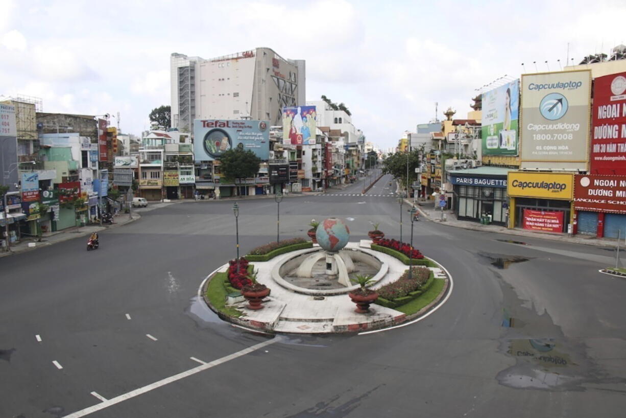 People ride on a motorcycle through a quiet intersection in Ho Chi Minh City, Vietnam, Monday, Aug. 23, 2021. Vietnam's largest metropolis Ho Chi Minh City has ordered a strict lockdown to help curb a worsening outbreak of the pandemic.