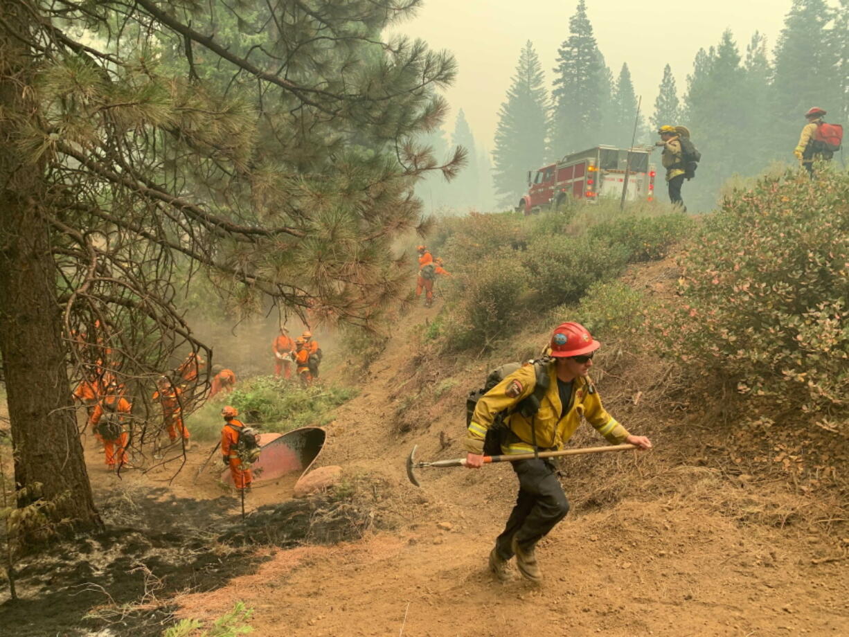 CalFire firefighters and California Correctional Center (CCC) inmates fight a spot fire on the side of Highway CA-36 between Chester and Westwood in Plumas County, Calif., Friday, Aug. 13, 2021. In California, the Dixie Fire that virtually destroyed the Sierra Nevada town of Greenville is less than a third surrounded. Fire officials say Northern California will have dangerous fire weather on Friday, including possible lightning that could spark more blazes. Climate change has made the U.S. West warmer and drier in the past 30 years and will continue to make the weather more extreme and wildfires more destructive, according to scientists.