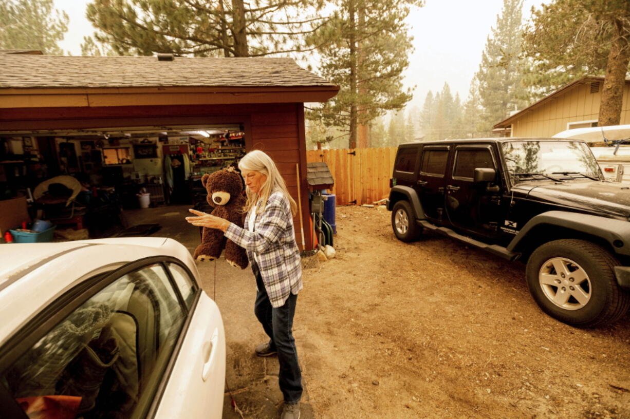 As the Caldor Fire approaches, Patty Kingsbury carries a teddy bear while evacuating from her South Lake Tahoe, Calif., home on Friday, Aug. 27, 2021.