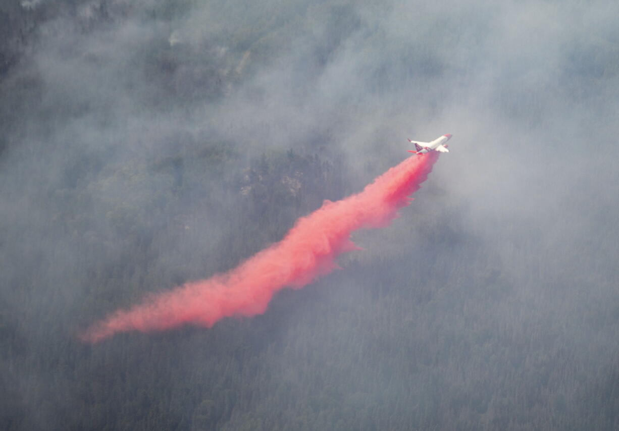 An aircraft drops red fire retardant onto the Greenwood Fire, about 50 miles north of Duluth, Minn., Tuesday, Aug. 17, 2021, as seen from an airplane above the temporary flight restriction zone.