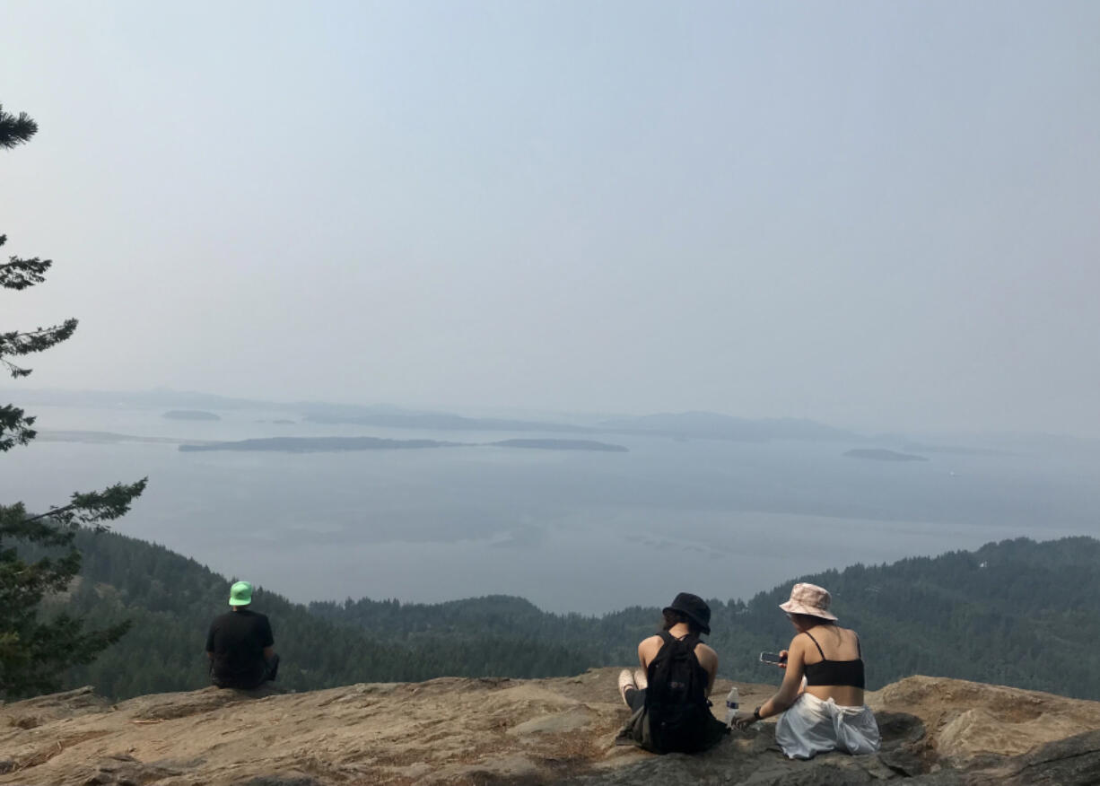 Hikers on the ledge at Oyster Dome, the rocky viewpoint on Mount Blanchard that affords panoramic views of the San Juan Islands and the Salish Sea.