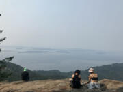 Hikers on the ledge at Oyster Dome, the rocky viewpoint on Mount Blanchard that affords panoramic views of the San Juan Islands and the Salish Sea.