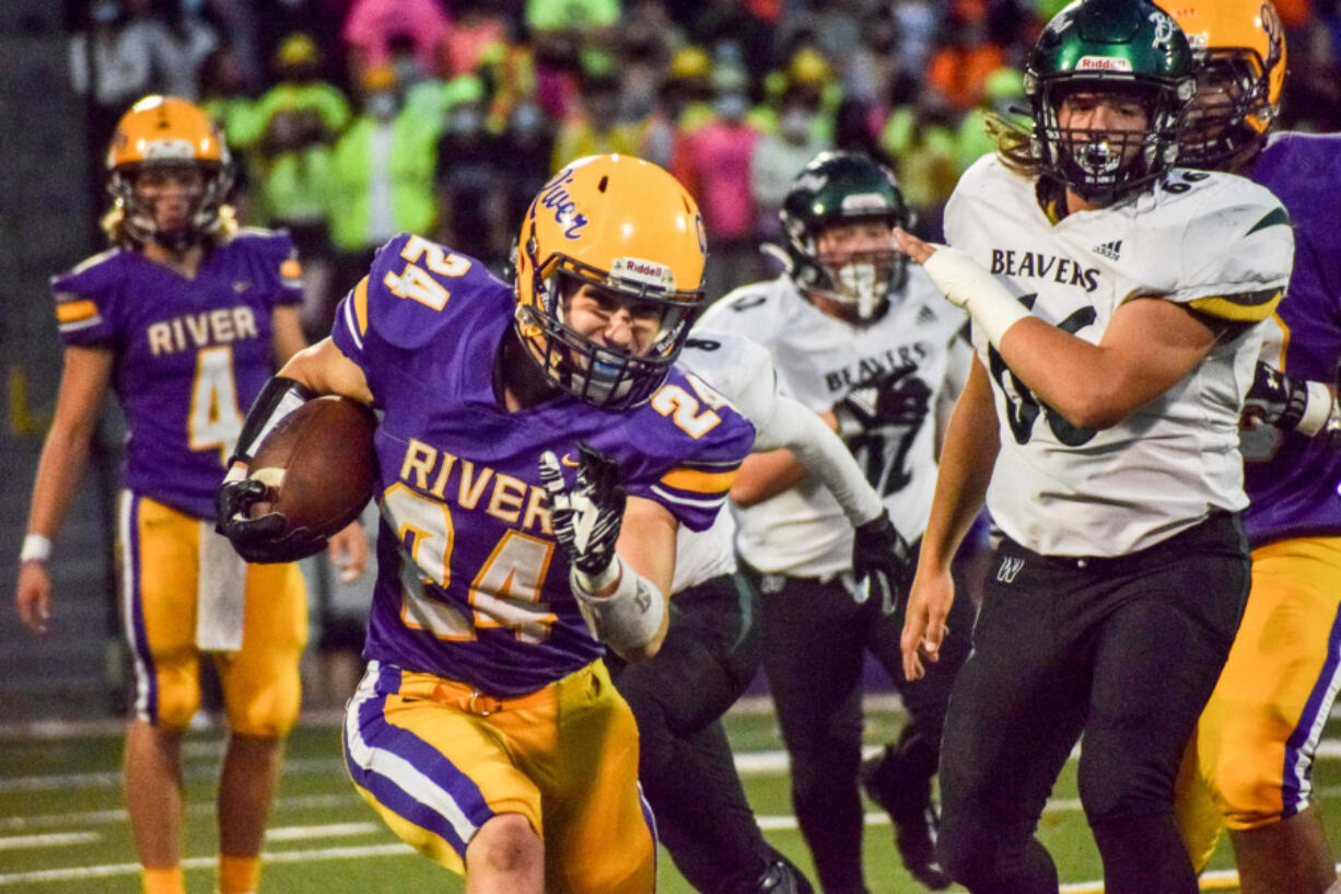 Columbia River's Kaden MacDonald (24) runs past Woodland? Tuker Ripp (66) during River's 16-7 over the Beavers on Friday, Sept.