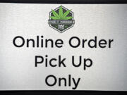 A sign inside Main Street Marijuana directs customers where to pick up their online orders on Aug. 24. Cannabis retailers had to suspend curbside and walk-up service last month, but the state Liquor and Cannabis Board announced Thursday that it would reinstate the allowances for another two months.