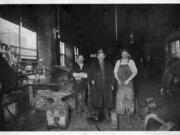 Three men inside Cooper's Blacksmith Shop at Fifth Street and Broadway in Vancouver interrupt their work to pose for a photo. From left to right: owner M.J. Cooper, J.E. Johnson and Heckman (first name unknown). In the horse-drawn era, blacksmiths forged tools, wheel rims and every tool they used. Blacksmith shops often attracted local men who chewed, smoked and exchanged gossip.