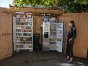 Gretta Anderson looks over contents of the free food pantry and fridge at her Vancouver home Monday afternoon. The Vancouver Free Fridge project is up to three fridges, but they're also being regulated by city codes over the structures, causing program leaders to start a petition.