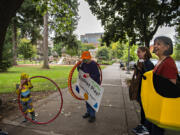 Ezra Little, 3, of Portland, from left, checks out a grown-up sized hula hoop while greeting Columbia Play Project performers Mary Sisson, Maureen Montague and Jeanne Bennett for a Give More 24! fundraiser Thursday morning at Esther Short Park in downtown Vancouver. The nonprofit set its fundraising goal at $10,000 and had received nearly $8,000 by late afternoon.