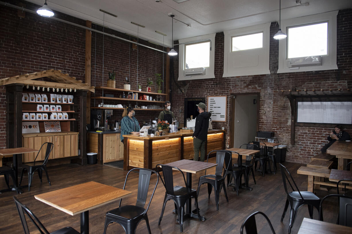 Barista Emily Cortez, from left, joins Marty Lopes, owner of Terrain Coffee Project, as they chat with customer Todd Sturtz of Vancouver at the new downtown Vancouver coffee shop on Tuesday morning.