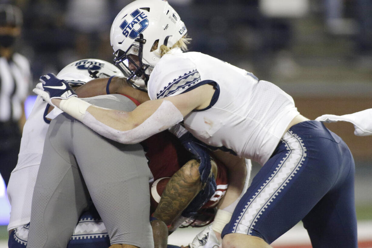 Utah State defensive end Patrick Joyner Jr., left, and linebacker Justin Rice, right, tackle Washington State quarterback Jarrett Guarantano for a safety during the first half of an NCAA college football game Saturday, Sept. 4, 2021, in Pullman, Wash.