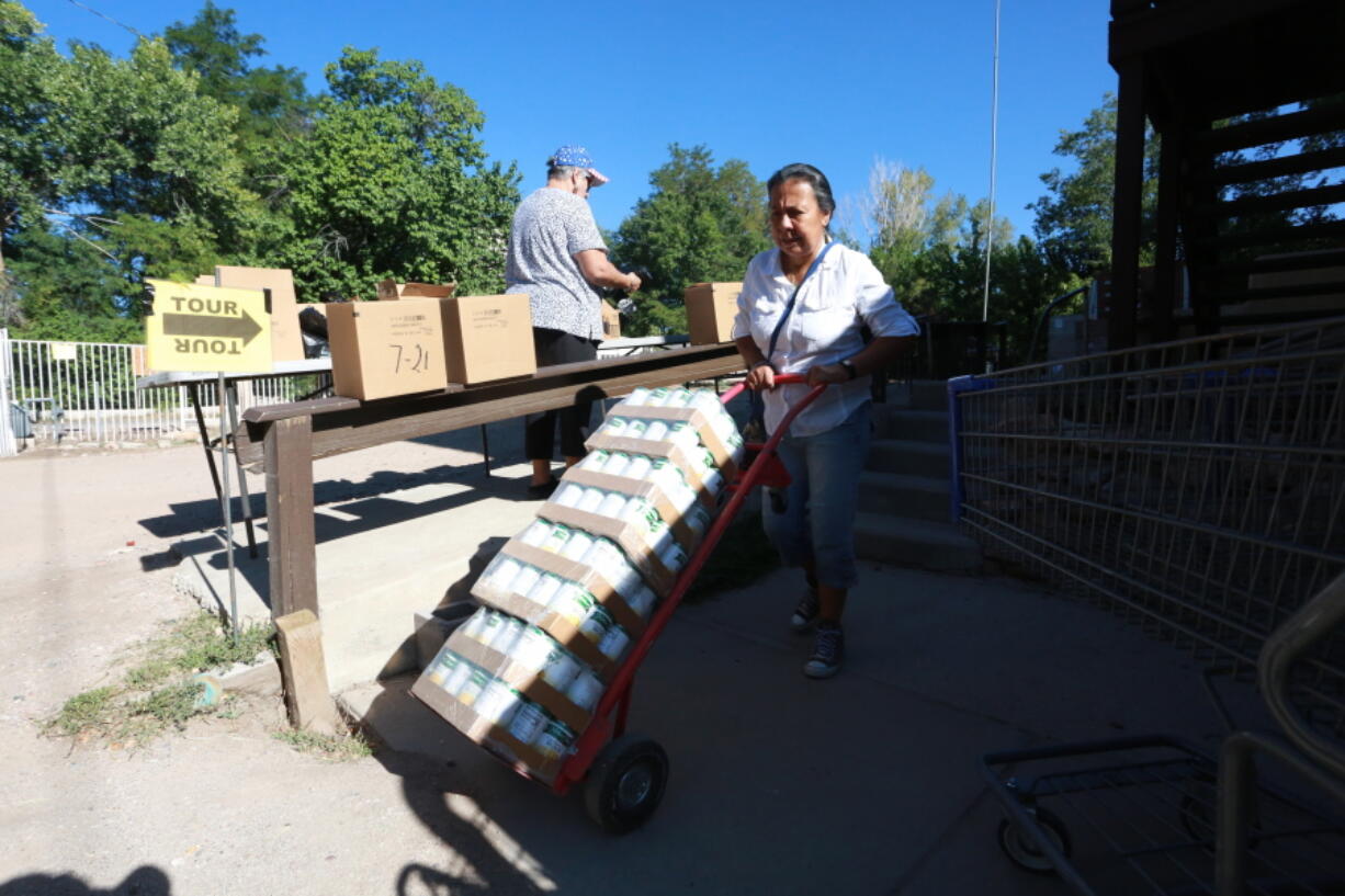 Barrios Unidos president Lupe Salazar pushes a dolly filled with canned food ahead of a food drive on Thursday, Sept. 23, 2021, in Chimay?, New Mexico.