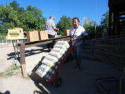 Barrios Unidos president Lupe Salazar pushes a dolly filled with canned food ahead of a food drive on Thursday, Sept. 23, 2021, in Chimay?, New Mexico.