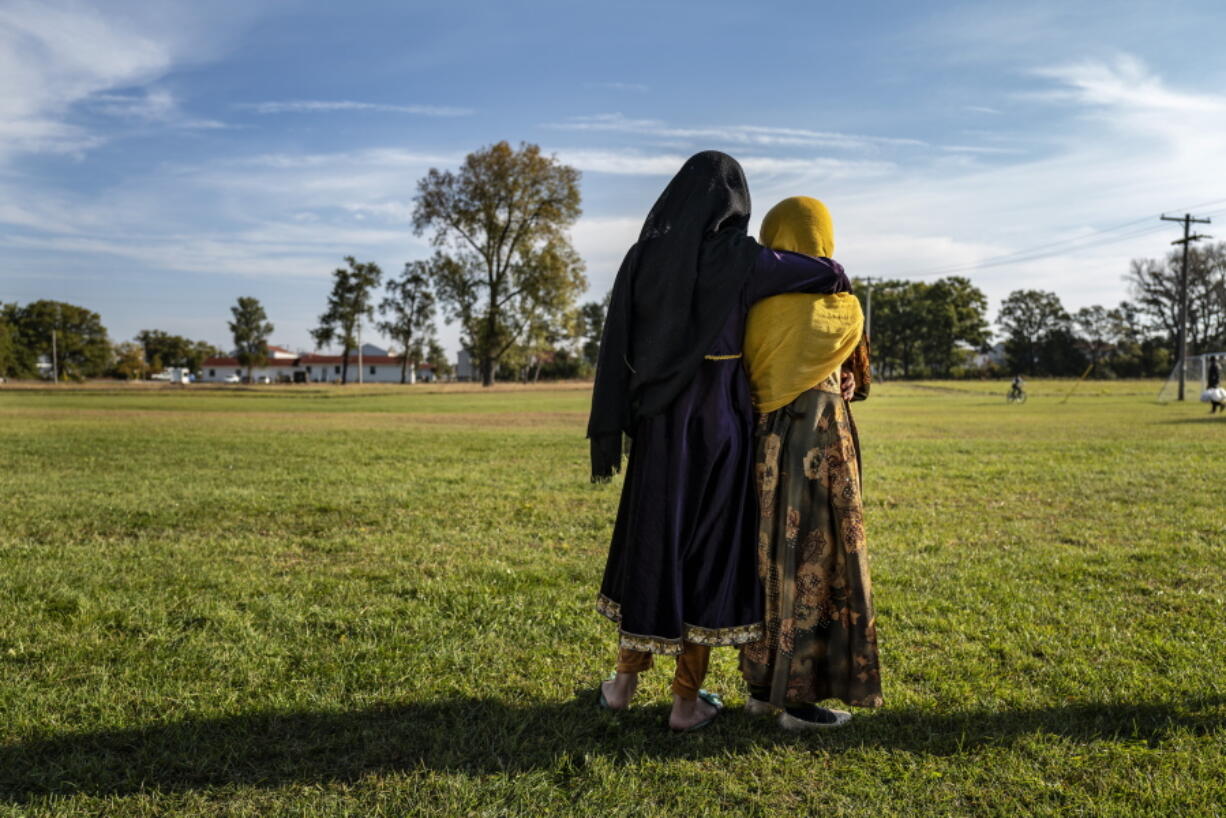 Afghan refugee girls watch a soccer game from a distance near the Village at the Ft. McCoy U.S. Army base on Thursday, Sept. 30, 2021 in Ft. McCoy, Wis.   The fort is one of eight military installations across the country that are temporarily housing the tens of thousands of Afghans who were forced to flee their homeland in August after the U.S. withdrew its forces from Afghanistan and the Taliban took control.