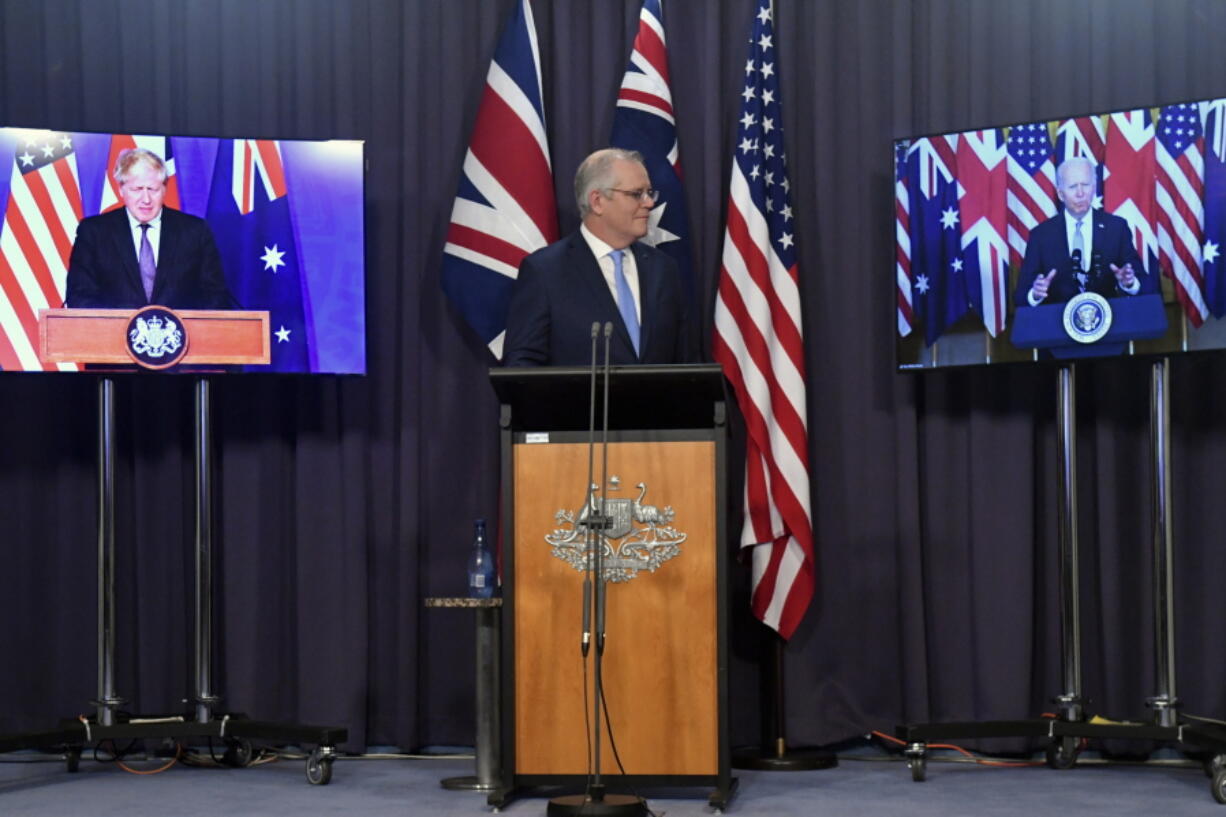 Australia's Prime Minister Scott Morrison, center, appears on stage with video links to Britain's Prime Minister Boris Johnson, left, and U.S. President Joe Biden at a joint press conference at Parliament House in Canberra, Thursday, Sept. 16, 2021. The leaders are announcing a security alliance that will allow for greater sharing of defense capabilities -- including helping equip Australia with nuclear-powered submarines.