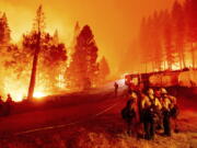 FILE - In this Thursday, Aug. 26, 2021 file photo, the Caldor Fire burns along both sides of Highway 50 as firefighters work to stop its eastward spread in Eldorado National Forest, Calif.. Last week, managers overseeing the fight against the massive wildfire scorching California's Lake Tahoe region thought they could have it contained by the start of this week. Instead, on Monday, Aug. 30, 2021, the Caldor Fire crested the Sierra Nevada, forcing the unprecedented evacuation of all 22,000 residents of South Lake Tahoe.