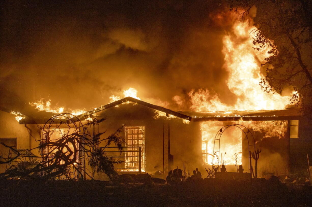 FILE - In this Sept. 27, 2020, file photo, a house burns on Platina Road at the Zogg Fire near Ono, Calif.  Pacific Gas & Electric has been charged with manslaughter and other crimes, Friday, Sept. 24, 2021,  in a Northern California wildfire last year that killed four people and destroyed hundreds of homes.