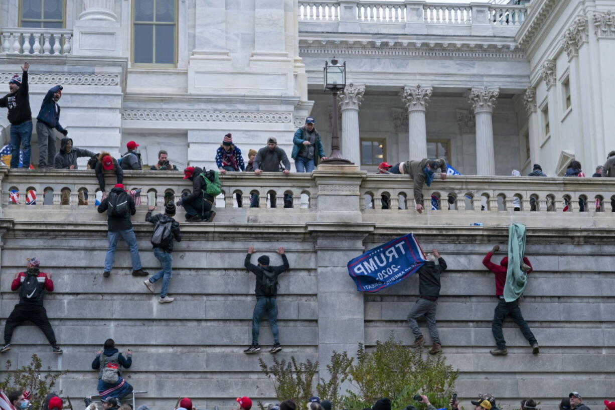 FILE - In this Jan. 6, 2021 file photo, rioters climb the west wall of the the U.S. Capitol in Washington. A House committee investigating the U.S. Capitol insurrection has requested that telecommunications and social media companies preserve the personal communications of hundreds of people who may have somehow been connected to the attack.