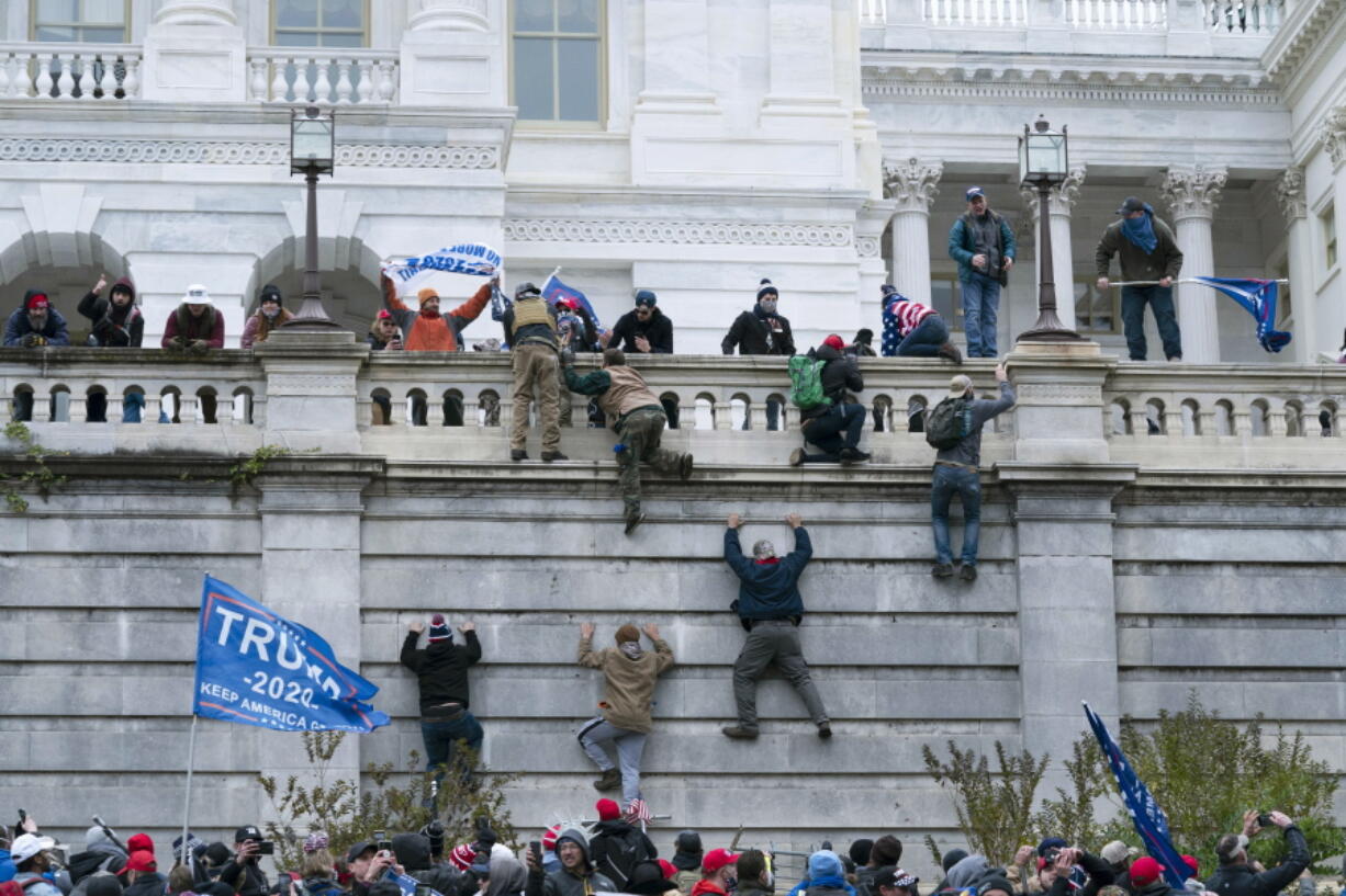 FILE - In this Jan. 6, 2021 file photo, violent insurrectionists loyal to President Donald Trump scale the west wall of the the U.S. Capitol in Washington. In the nearly nine months since Jan. 6, federal agents have managed to track down and arrest more than 600 people across the U.S. believed to have joined in the riot at the Capitol. Getting those cases swiftly to trial is turning out to be an even more difficult task.