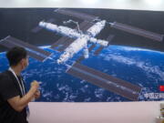 A visitor looks at a mural showing an artist's rendering of China's space station at the World Robot Conference in Beijing, Saturday, Sept. 11, 2021. Three Chinese astronauts have departed from the country's orbiting space station in preparation for returning to Earth after 90 days in orbit, the national space agency reported Thursday, Sept. 16, 2021.