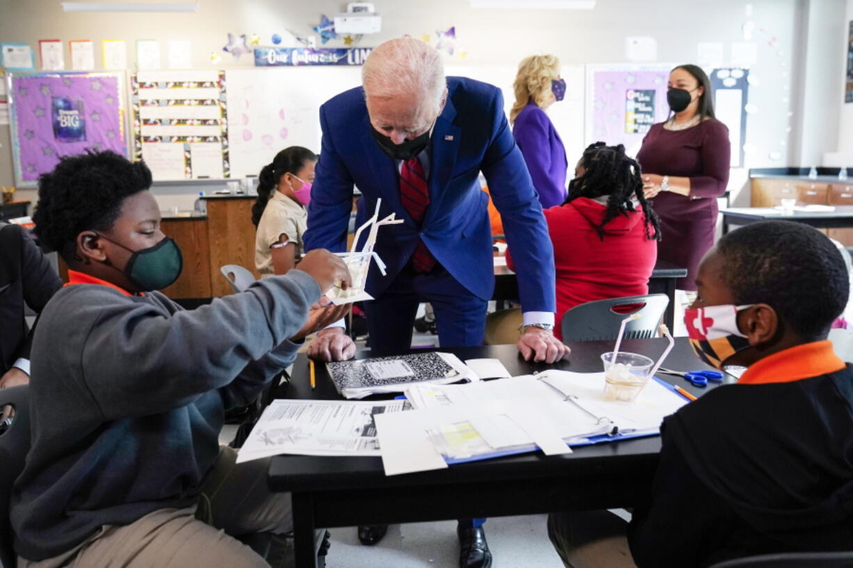 FILE - In this Sept. 10, 2021, file photo President Joe Biden talks to students at Brookland Middle School in Washington, as first lady Jill Biden talks with Brookland Middle School science teacher Michelle Taylor, right rear. As Democrats push ahead with Biden's $3.5 trillion rebuilding plan, they are promising historic investments across all levels of education. The proposal includes universal prekindergarten, two years of free community college and expanded child care subsidies, among others.