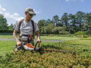 Tyler Campbell uses an electric hedgetrimmer to trim hedges at the New York Botanical Garden in the Bronx borough of New York.