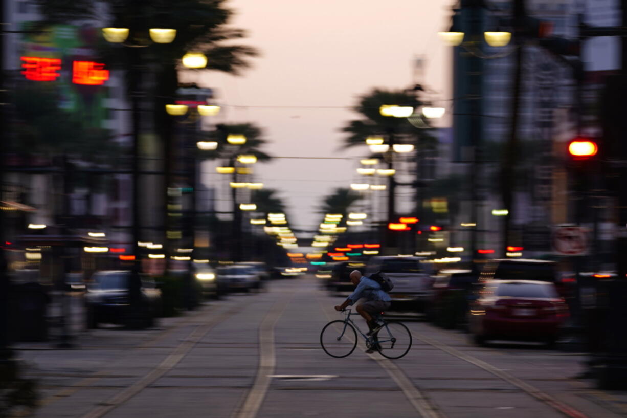 In the aftermath of Hurricane Ida, a man rides his bike across Canal Street, Saturday, Sept. 4, 2021, in the French Quarter of New Orleans.