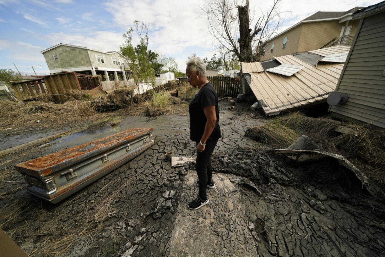 Audrey Trufant Salvant stands near a casket that floated in floodwaters from a nearby cemetery to her home in Ironton, La., Monday, Sept. 27, 2021. A month after Hurricane Ida roared ashore with 150-mph (241-kph) winds, communities all along the state's southeastern coast -- Ironton, Grand Isle, Houma, Lafitte and Barataria -- are still suffering from the devastating effects of the Category 4 storm.