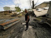 Audrey Trufant Salvant stands near a casket that floated in floodwaters from a nearby cemetery to her home in Ironton, La., Monday, Sept. 27, 2021. A month after Hurricane Ida roared ashore with 150-mph (241-kph) winds, communities all along the state's southeastern coast -- Ironton, Grand Isle, Houma, Lafitte and Barataria -- are still suffering from the devastating effects of the Category 4 storm.