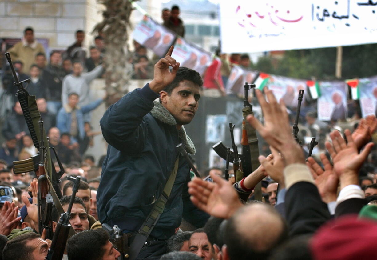 FILE - In this Dec. 30, 2004 file photo, Zakaria Zubeidi, then leader in the Al Aqsa Martyrs Brigade in the West Bank, is carried by supporters during a presidential elections campaign rally in support of Mahmoud Abbas, in the West Bank town of Jenin. For nearly two decades, Zubeidi has been an object of fascination for Israelis and Palestinians alike, who have seen his progression from a child actor to a swaggering militant, to the scarred face of a West Bank theater promoting "cultural resistance" to Israeli occupation. In his latest act, he has emerged as one of Israel's most wanted fugitives after tunneling out of a high-security prison on Monday, Sept. 6, 2021, with five other Palestinian militants.