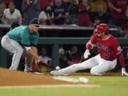 Los Angeles Angels designated hitter Shohei Ohtani, right, slides into third for a an RBI triple ahead of the tag of Seattle Mariners third baseman Kyle Seager during the third inning of a baseball game Saturday, Sept. 25, 2021, in Anaheim, Calif. (AP Photo/Mark J.