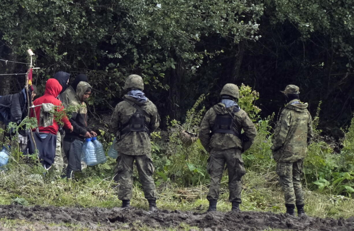 Migrants stuck along the Poland-Belarus border carry plastic water bottles as they are surrounded by Polish forces in Usnarz Gorny, Poland, on Wednesday, Sept. 1, 2021. Poland has been reinforcing its border with Belarus - also part of the EU's eastern border - after thousands of migrants from Iraq, Afghanistan and elsewhere tried to illegally enter the country. The Polish government says it is the target of a "hybrid war" waged by authoritarian Belarus. Human rights activists are concerned about a group caught along the border, trapped between armed guards on each side.