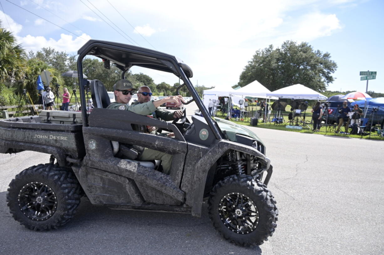 Florida Fish and Wildlife Commission officers ride past media stationed at the entrance of the Carlton Reserve during a search for Brian Laundrie, Tuesday, Sept. 21, 2021, in Venice, Fla. Laundrie is a person of interest in the disappearance of his girlfriend, Gabrielle "Gabby" Petito. (AP Photo/Phelan M.