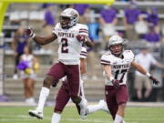 Montana's Gavin Robertson (2) leaps in celebration after making an interception against Washington as teammate Robby Hauck follows in the first half of an NCAA college football game Saturday, Sept. 4, 2021, in Seattle.