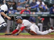 Boston Red Sox's Rafael Devers, right, scores as Seattle Mariners catcher Tom Murphy waits for the ball in the 10th inning of a baseball game Wednesday, Sept. 15, 2021, in Seattle.