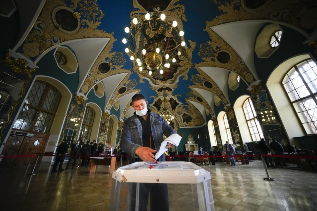 A man casts his ballot at a polling station at the Kazansky railway station during the Parliamentary elections in Moscow, Russia, Saturday, Sept. 18, 2021.  Sunday will be the last of three days voting for a new parliament, but there seems to be no expectation that United Russia, the party devoted to President Vladimir Putin, will lose its dominance in the State Duma.