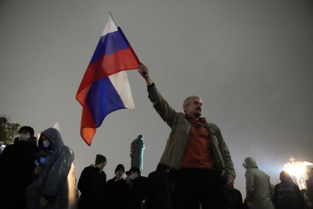 FILE - In this Monday, Sept. 20, 2021 file photo, a demonstrator holds a Russian national flag during a protest against the results of the Parliamentary election in Moscow, Russia. A group of politicians and activists who lost to their Kremlin-backed opponents in Russia's parliamentary election last weekend have formed a coalition to contest the results from online voting in the Russian capital, which they believe was rigged and blame for their defeat.