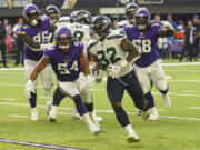 Seattle Seahawks running back Chris Carson (32) runs for a touchdown in front of Minnesota Vikings middle linebacker Eric Kendricks (54) and defensive tackle Michael Pierce (58) in the first half of an NFL football game in Minneapolis, Sunday, Sept. 26, 2021.